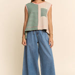 Woman wearing a colorful sleeveless top and blue jeans on a beige background