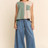 Woman wearing a colorful sleeveless top and blue jeans on a beige background