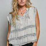 Woman wearing a sleeveless, patterned top against a plain background