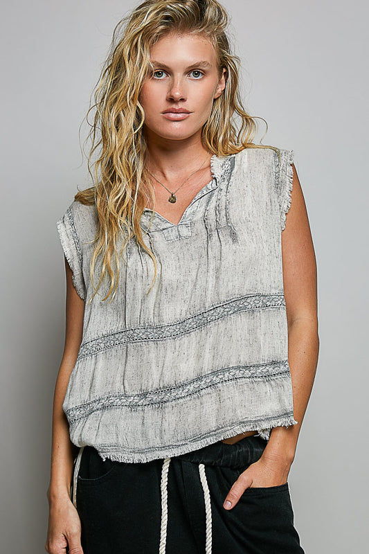 Woman wearing a sleeveless, patterned top against a plain background