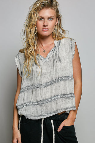 Woman wearing a sleeveless, patterned top against a plain background