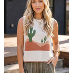Woman wearing a sleeveless top with a desert landscape design outdoors.