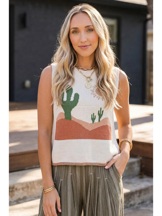 Woman wearing a sleeveless top with a desert landscape design outdoors.