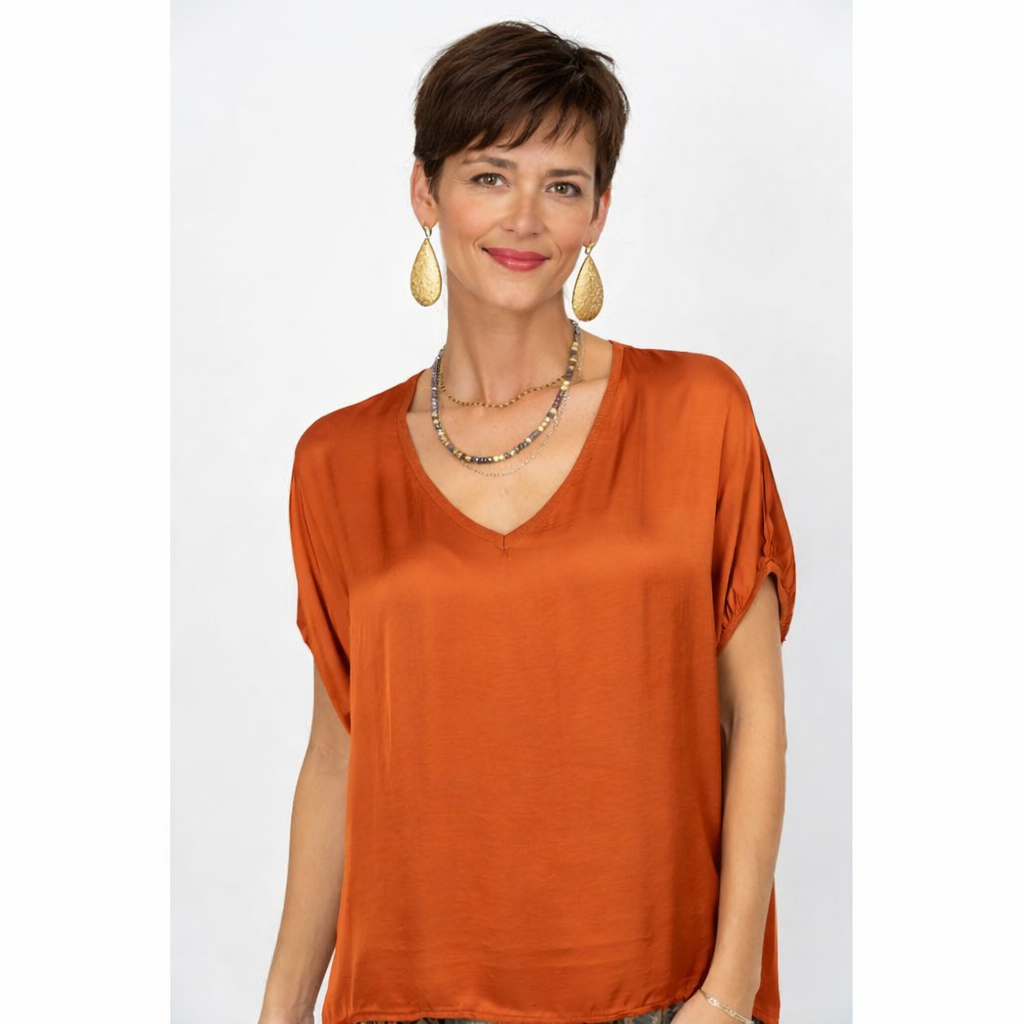 Woman wearing an orange blouse with a plain background