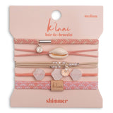 Packaged hair tie and bracelet set with shell and leaf charms on a pink background
