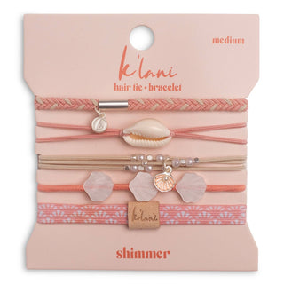 Packaged hair tie and bracelet set with shell and leaf charms on a pink background
