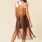 Woman wearing a fringed dress with a colorful top on a beige background