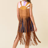 Woman wearing a fringed dress with a colorful top on a beige background