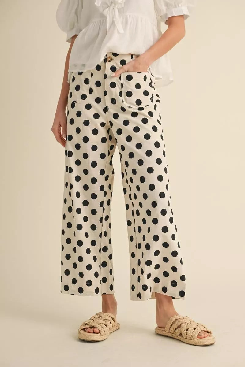 Person wearing polka dot pants and a white top on a beige background