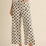 Person wearing polka dot pants and a white top on a beige background