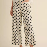 Person wearing polka dot pants and a white top on a beige background