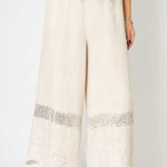 White wide-leg pants with decorative trim on a white background