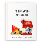 Birthday card with a dog in a birthday hat and a milk carton, featuring humorous text.