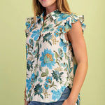 Woman wearing a floral blouse with ruffled sleeves against a light green background