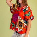 Woman wearing a colorful floral blouse against a green background