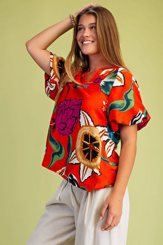 Woman wearing a colorful floral blouse against a green background