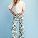 Woman wearing a white blouse and floral pants against a light blue background