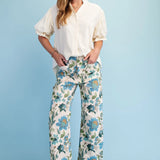 Woman wearing a white blouse and floral pants against a light blue background