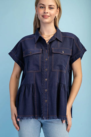 Woman wearing a navy denim shirt with short sleeves against a light blue background