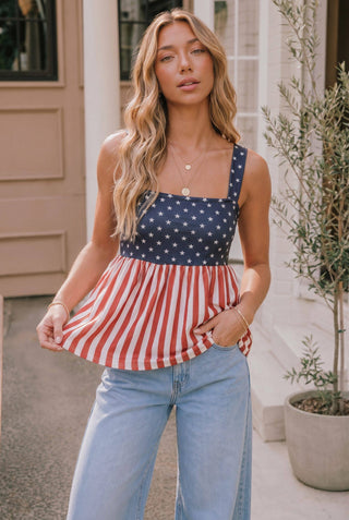 Woman wearing a red, white, and blue striped dress with a patterned top outdoors.