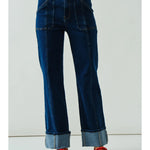 Blue jeans worn by a person with red shoes on a white background