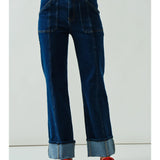 Blue jeans worn by a person with red shoes on a white background
