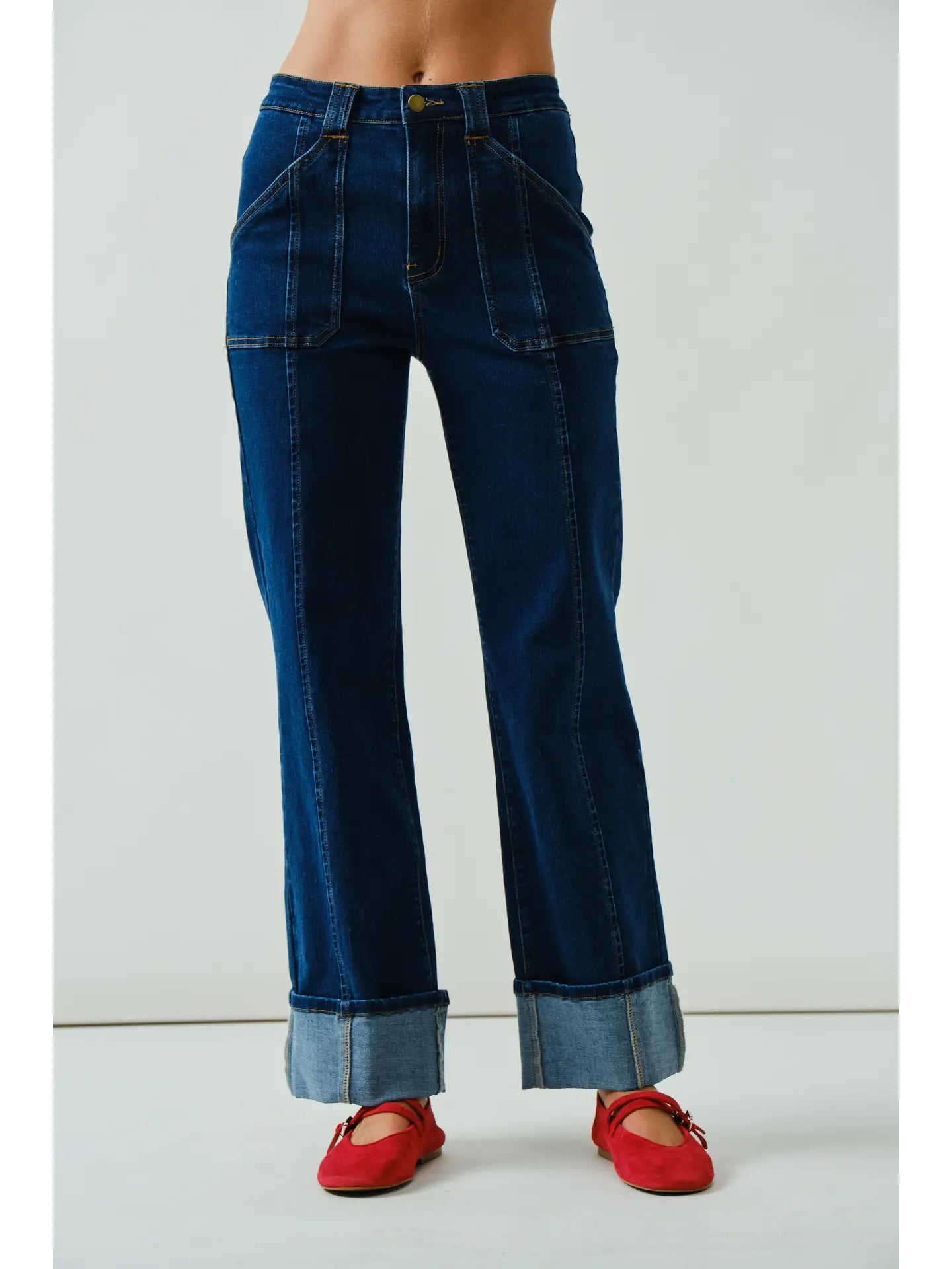 Blue jeans worn by a person with red shoes on a white background