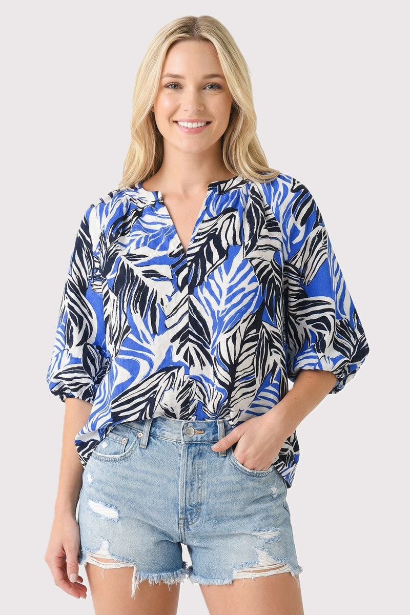 Woman wearing a blue and black patterned blouse with denim shorts on a white background