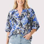 Woman wearing a blue and black patterned blouse with denim shorts on a white background