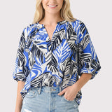 Woman wearing a blue and black patterned blouse with denim shorts on a white background