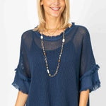 A woman wearing a blue mesh top with under tank, displaying frayed edges and a round neckline.
