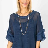 A woman wearing a blue mesh top with under tank, displaying frayed edges and a round neckline.