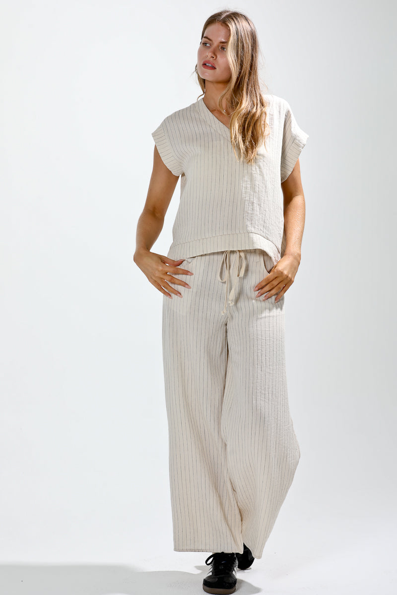 Woman wearing a sleeveless top and striped pants on a white background