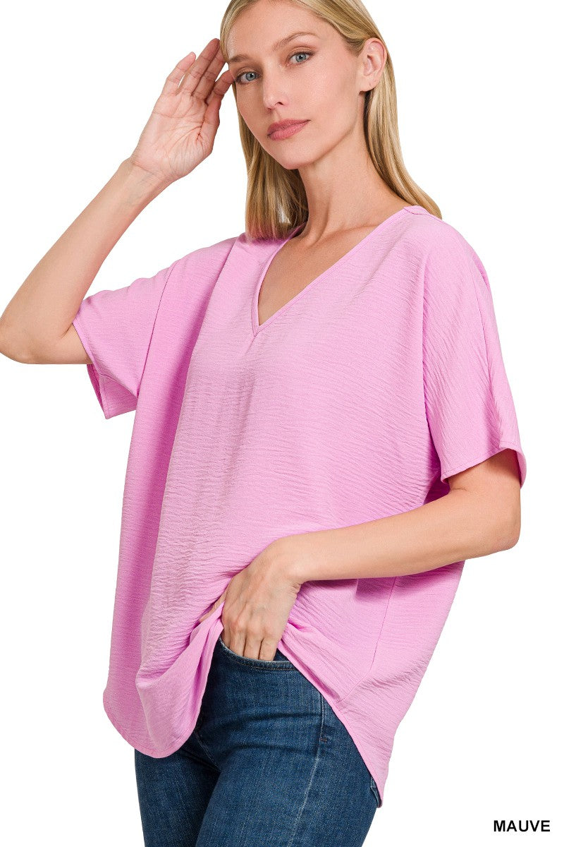 Woman wearing a mauve oversized top with a plain background