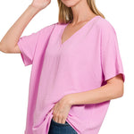 Woman wearing a mauve oversized top with a plain background