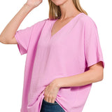 Woman wearing a mauve oversized top with a plain background