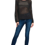 Woman wearing a black sheer top and blue jeans on a white background