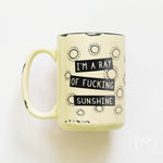 Yellow mug with black text and sun designs on a white background