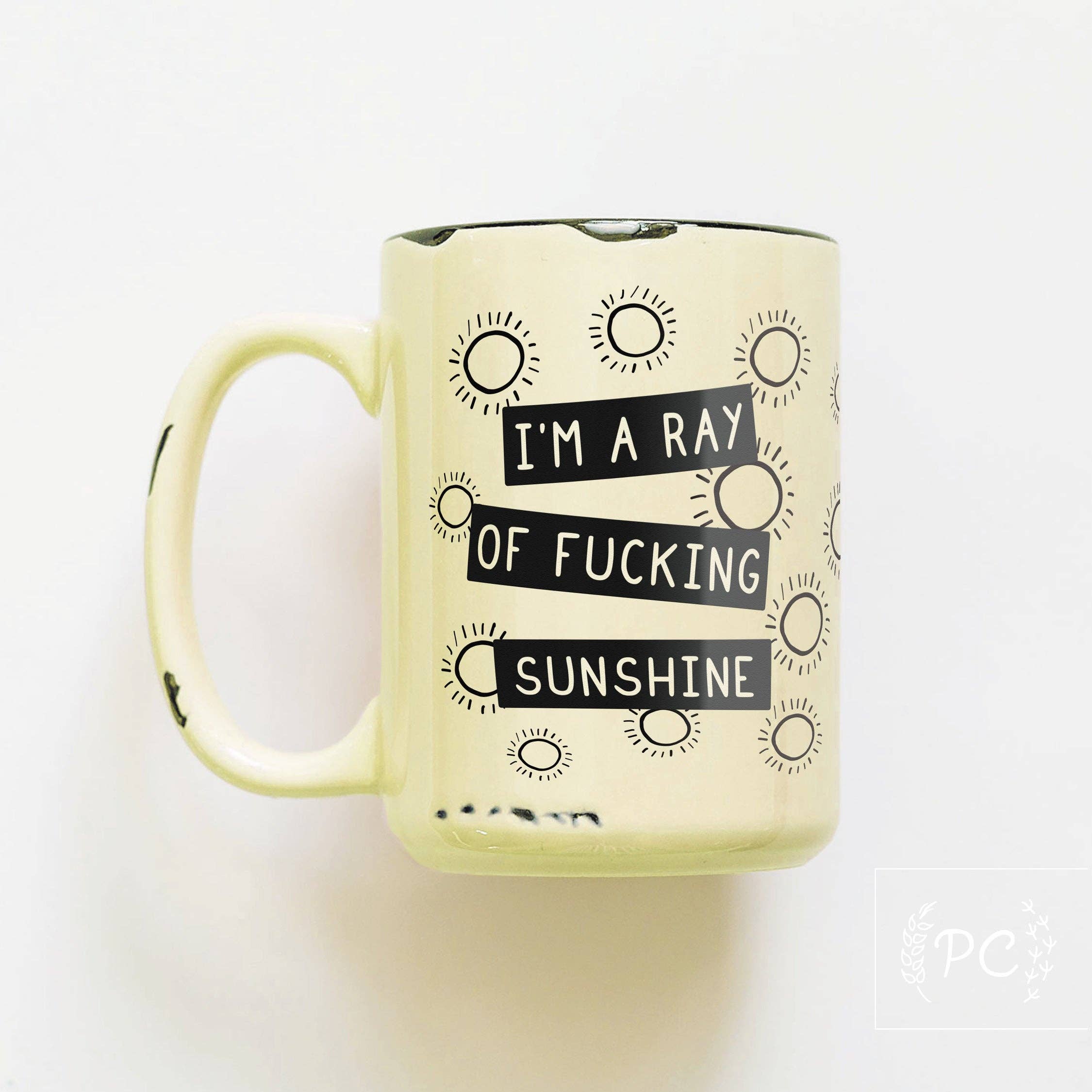 Yellow mug with black text and sun designs on a white background