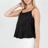 Woman wearing a black fringe top and white pants on a white background