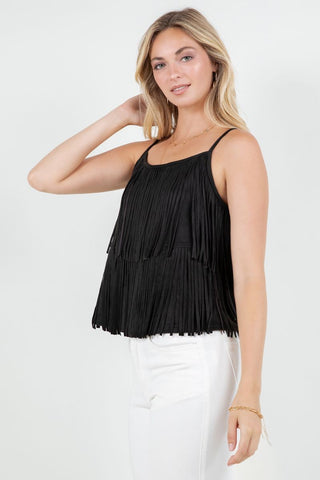 Woman wearing a black fringe top and white pants on a white background