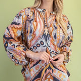 Woman wearing a patterned blouse against a green background