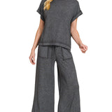 Woman wearing a gray outfit with wide-leg pants on a white background