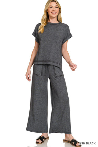 Woman wearing a gray outfit with wide-leg pants on a white background
