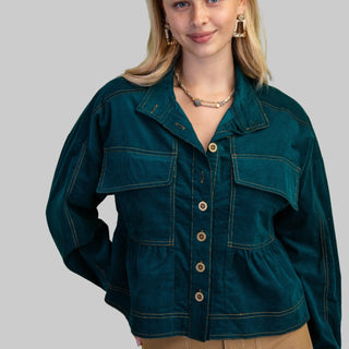 Woman wearing a teal jacket on a gray background