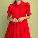 Woman wearing a red dress with puff sleeves against a green background