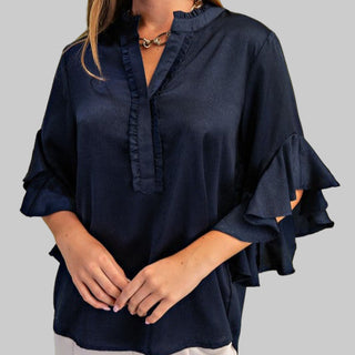Navy blue blouse with ruffled sleeves on a green background