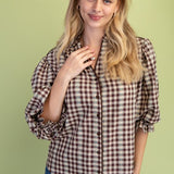 Woman wearing a plaid shirt and jeans against a green background