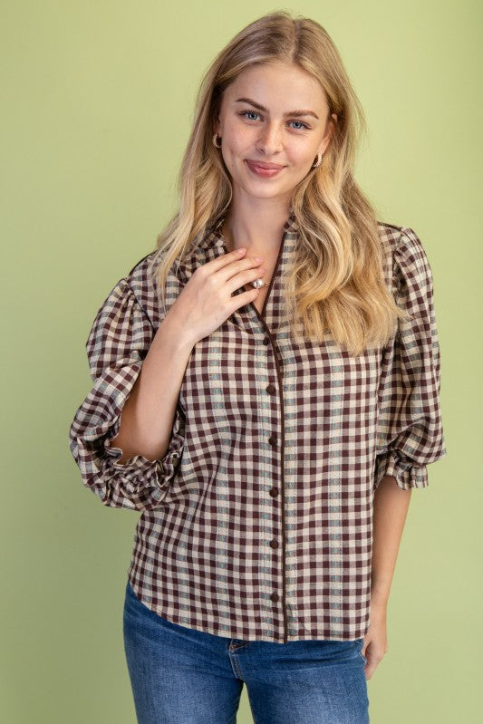 Woman wearing a plaid shirt and jeans against a green background