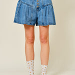 Denim shorts worn by a person on a plain background